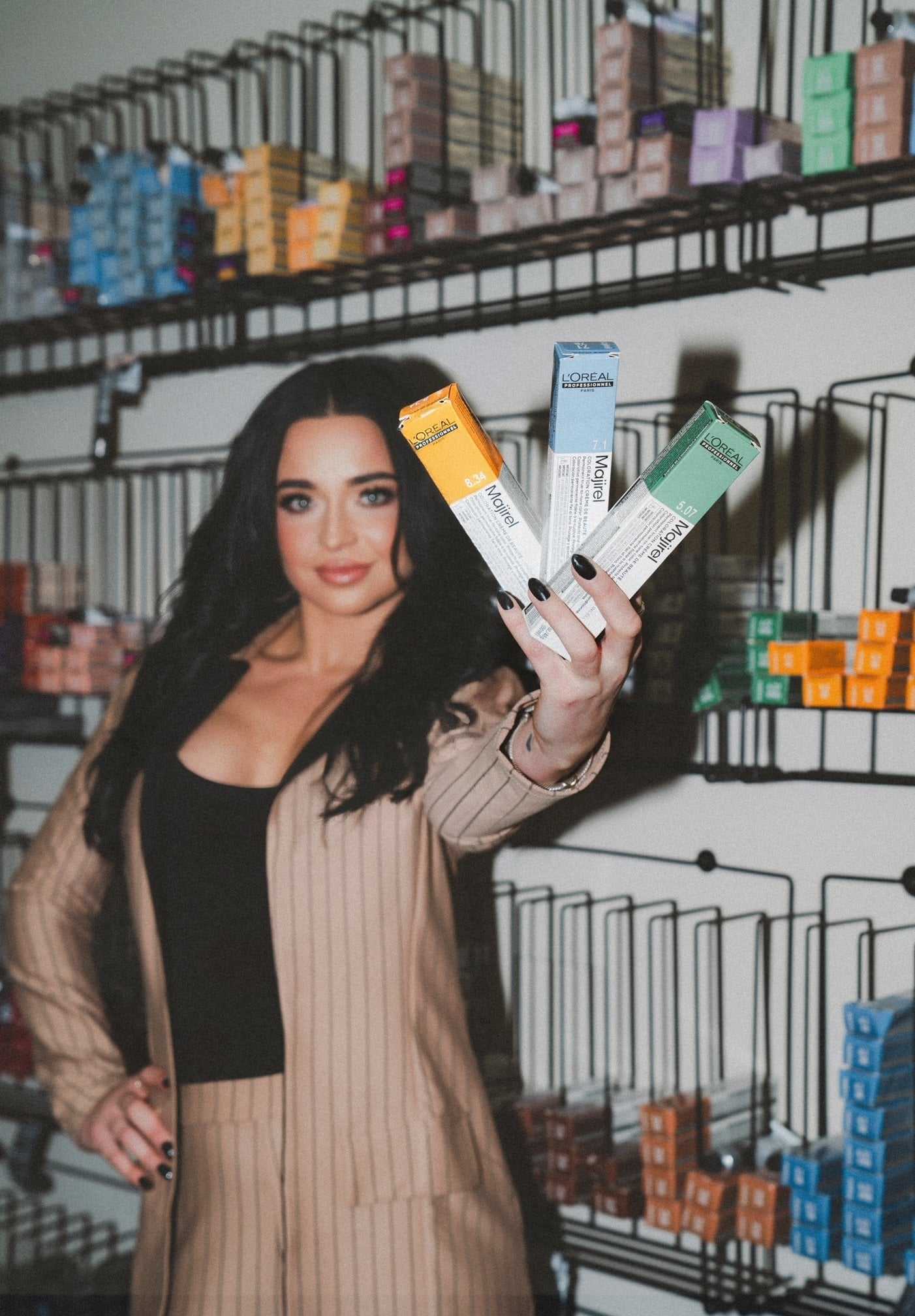 Woman holding vape products in a store with shelves of assorted boxes.
